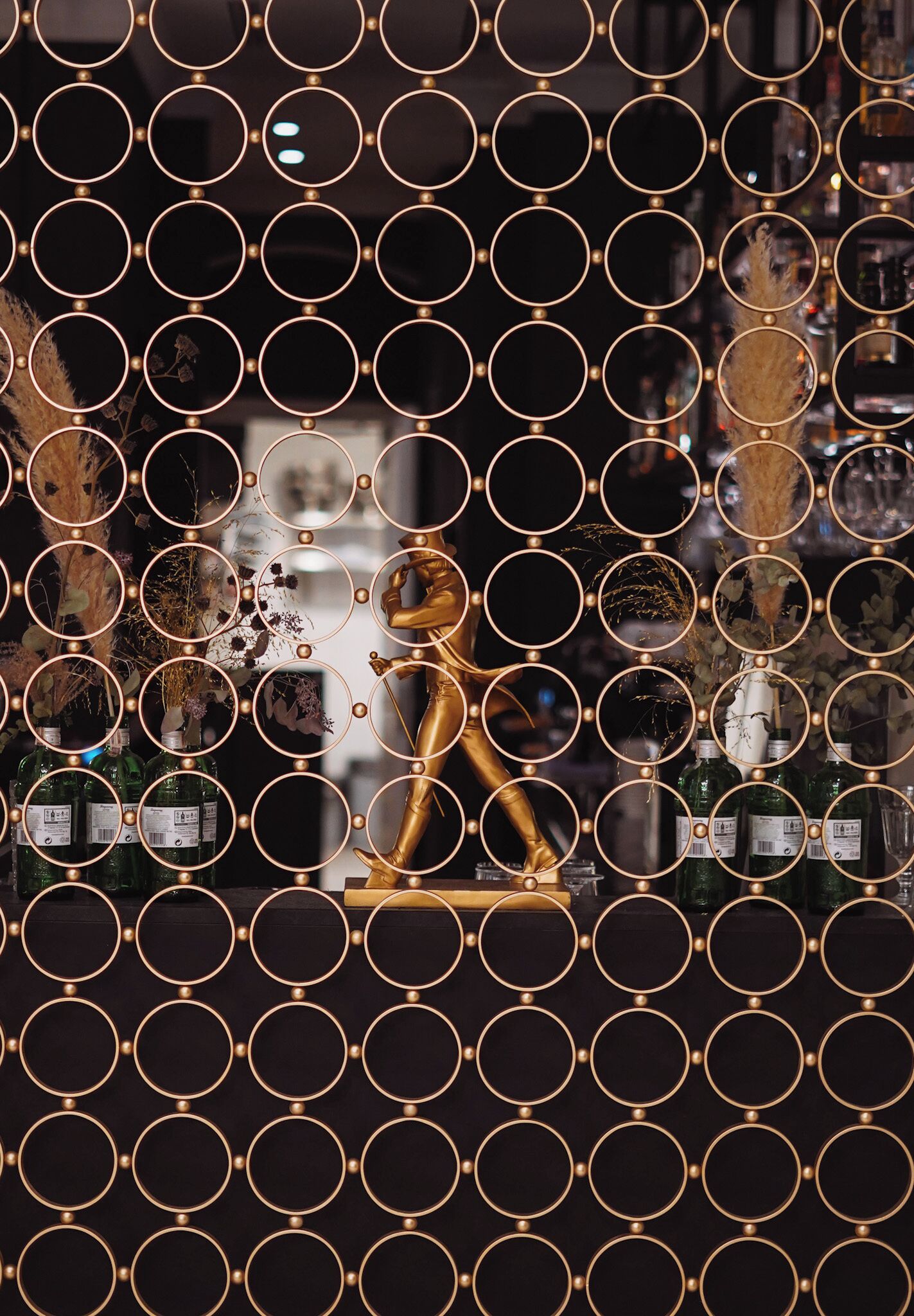 A room with a patterned wall, a statue, and bottles.