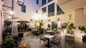 An outdoor dining area with tables and chairs, surrounded by potted plants and decorative lighting. - Hotel Saski Krakow, Curio Collection by Hilton (Kraków)