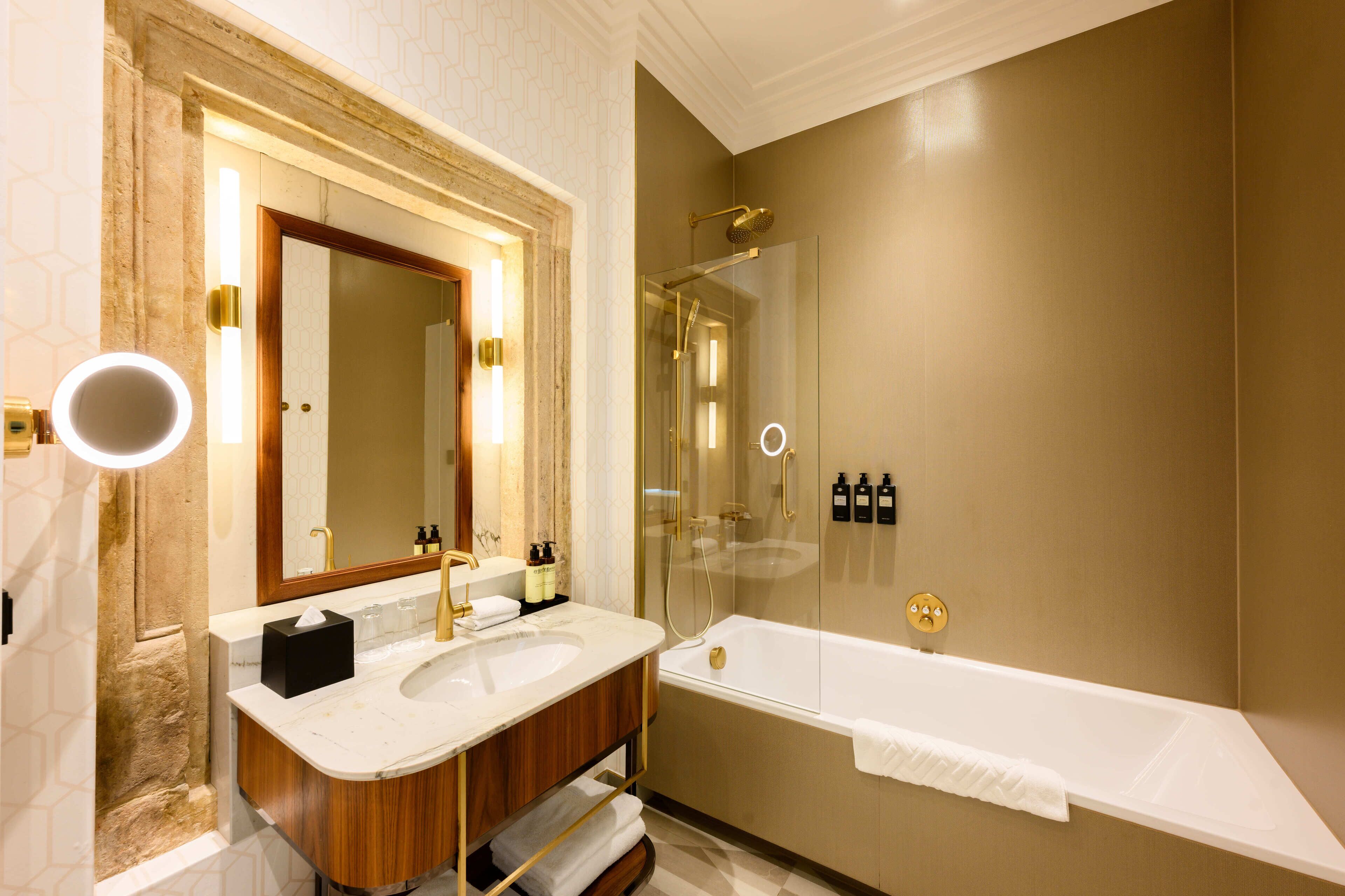 A modern bathroom with a large mirror, two sinks, a bathtub, and a glass-enclosed shower.