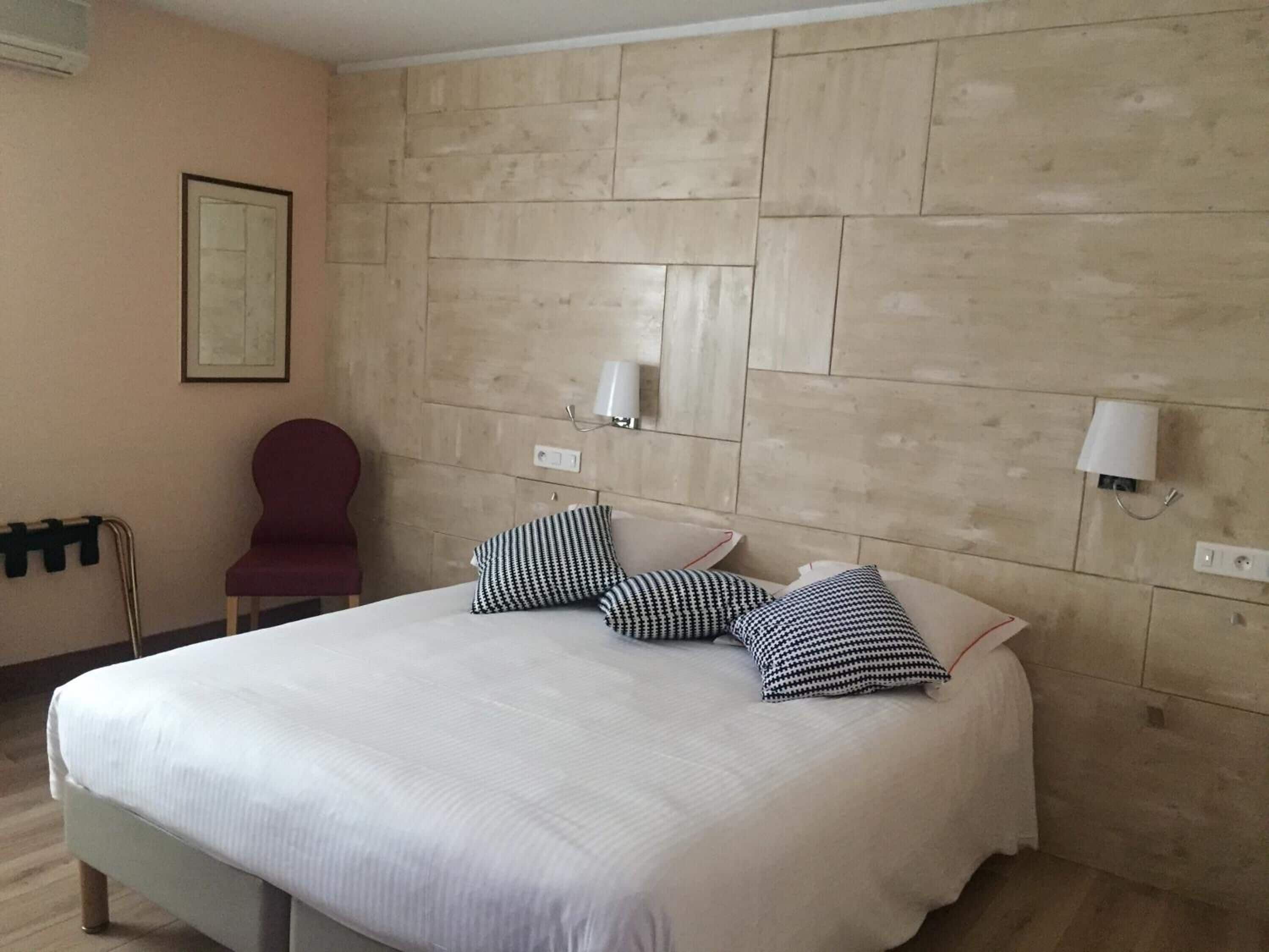 Une chambre d’hôtel avec un grand lit, un fauteuil rouge et un mur en bois.