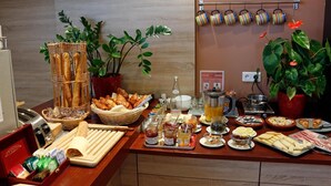 A buffet setup with various food items, including bread, pastries, and condiments.