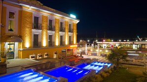 A hotel with a pool area, outdoor seating, and a well-lit facade.