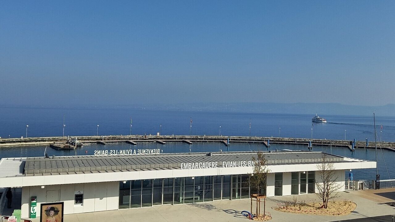 A waterfront building with a sign reading "EMBARCADRE EVIAN LES BAINES".