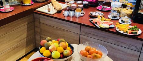 A breakfast buffet with various fruits, pastries, and cereals.