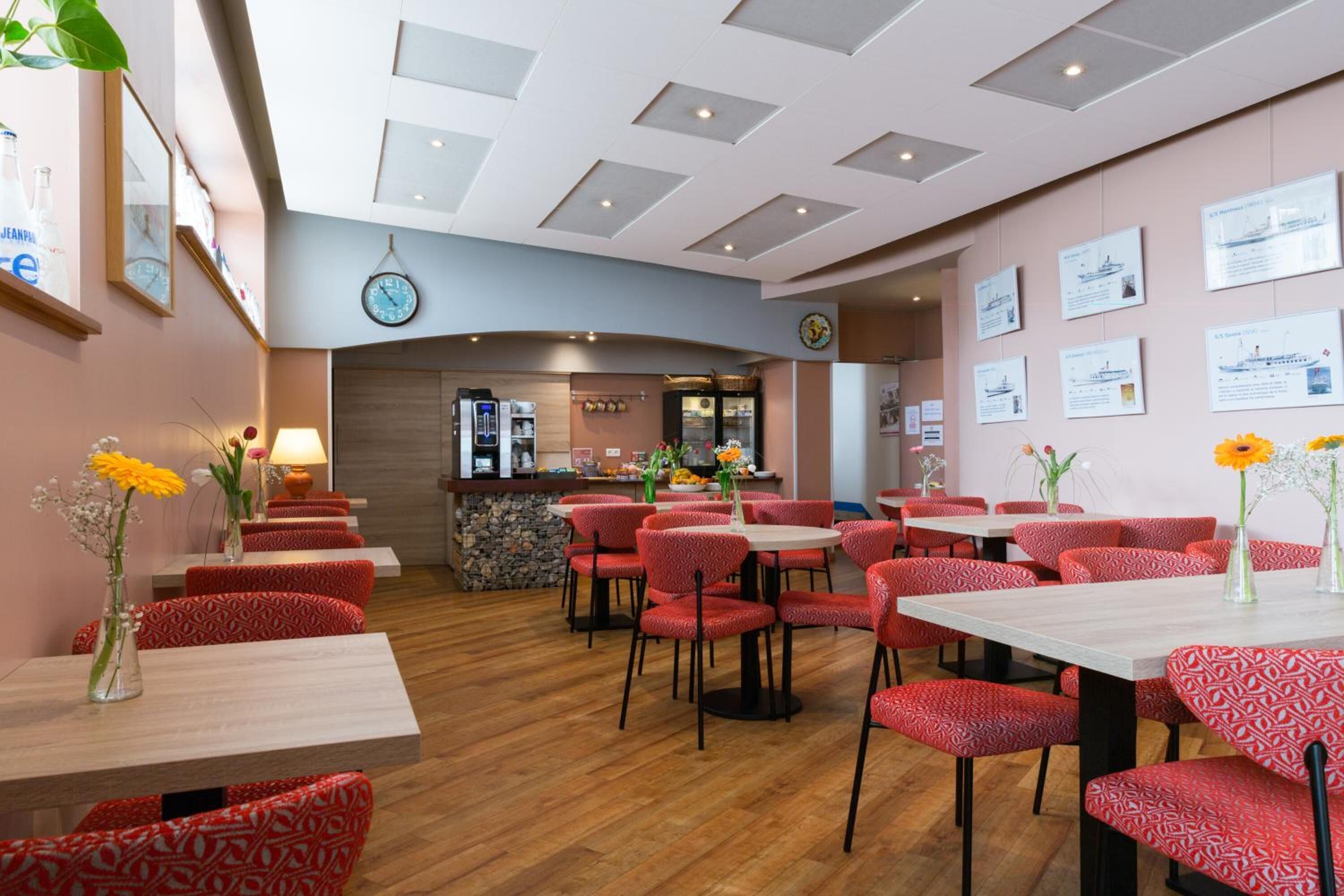 Een restaurant met rode gestreepte stoelen en tafels, een bar en informele posters aan de muur.