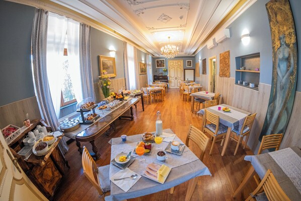 A dining area with a buffet setup, wooden tables, and chairs.