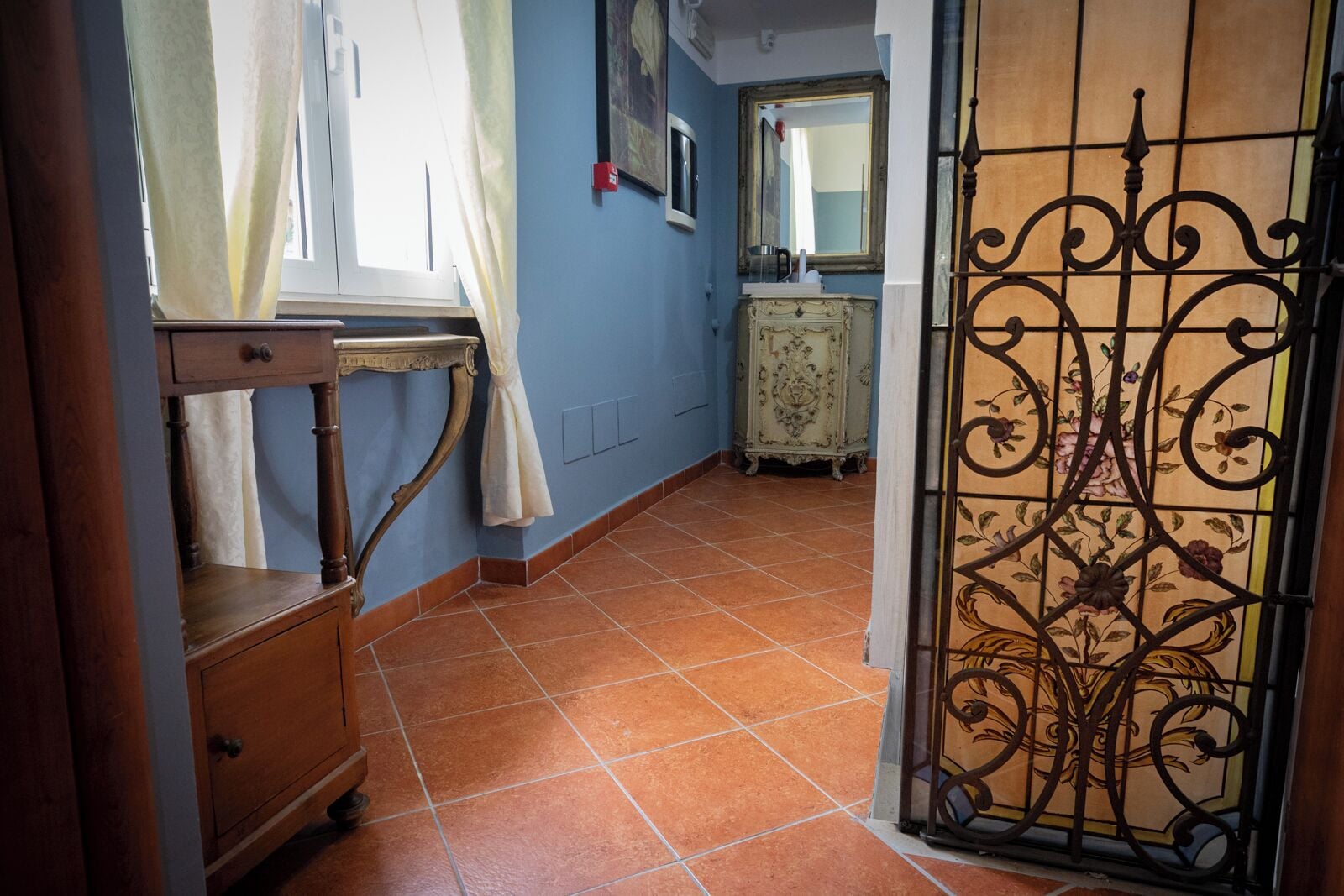 A hallway with a wooden dresser, a table, and a decorative iron gate.