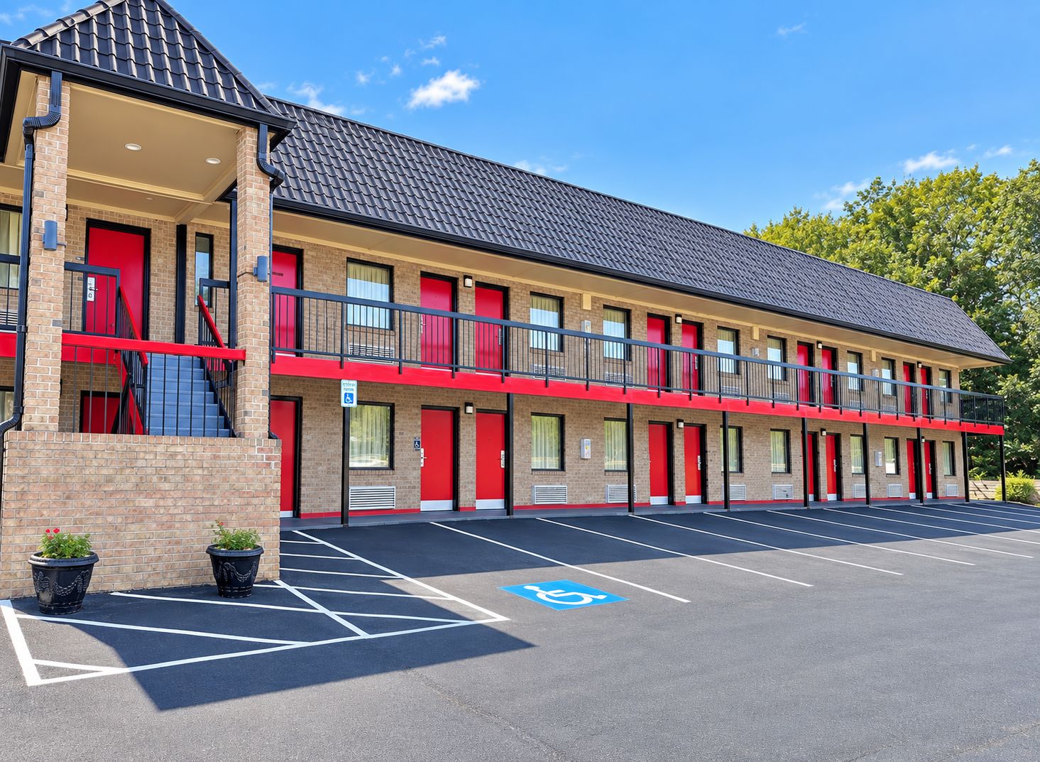A multi-story motel with red doors and balconies, a parking lot with handicapped parking, and brick walls.