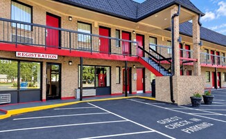 Hotel com balcão de recepção, escada e área de estacionamento com placa de check-in.