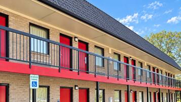 A multi-story motel with red doors and a parking lot.