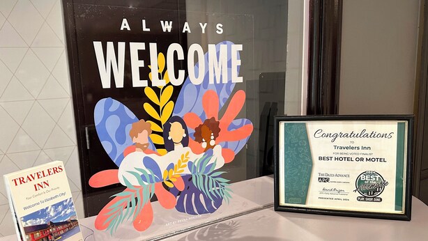 A framed award certificate for Travelers Inn, a welcome sign with colorful graphics, and a promotional brochure.