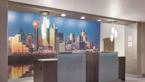 A reception desk with a cityscape mural, a glass partition, and a wooden panel.