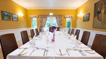 A dining room with a long table set for a formal meal, flanked by wooden chairs.