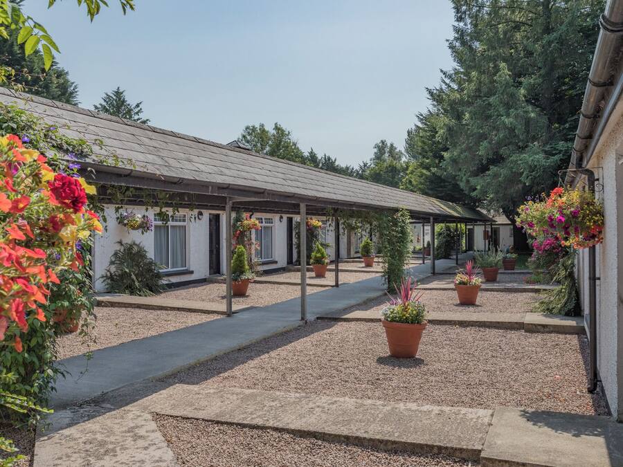 A covered outdoor area with a gravel path leading to a building with multiple windows.