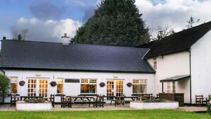 A white building with a dark roof, multiple windows, and outdoor seating. - Brown Trout Golf & Country Inn (Coleraine)