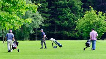 A golf course with three people walking with golf bags and equipment.
