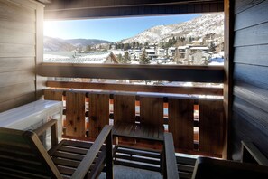A wooden balcony with a view of a snowy mountain town. - Highline Vail - a DoubleTree by Hilton (Vail)