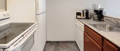 A compact kitchen with a stove, oven, and a coffee maker on the countertop.