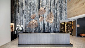 A hotel reception area with a modern design, featuring a wooden wall with vertical lines and a reception desk in the foreground. - Highline Vail - a DoubleTree by Hilton (Vail)