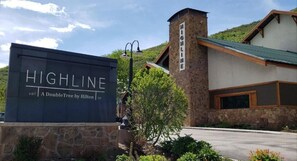 A hotel sign reading "HIGHLINE" with a stone building in the background. - Highline Vail - a DoubleTree by Hilton (Vail)