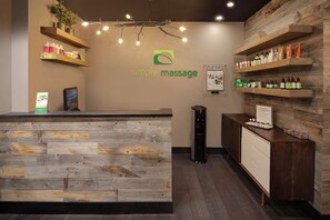 A reception area with a wooden reception desk, shelves with products, and a logo for 'Simply Massage'.