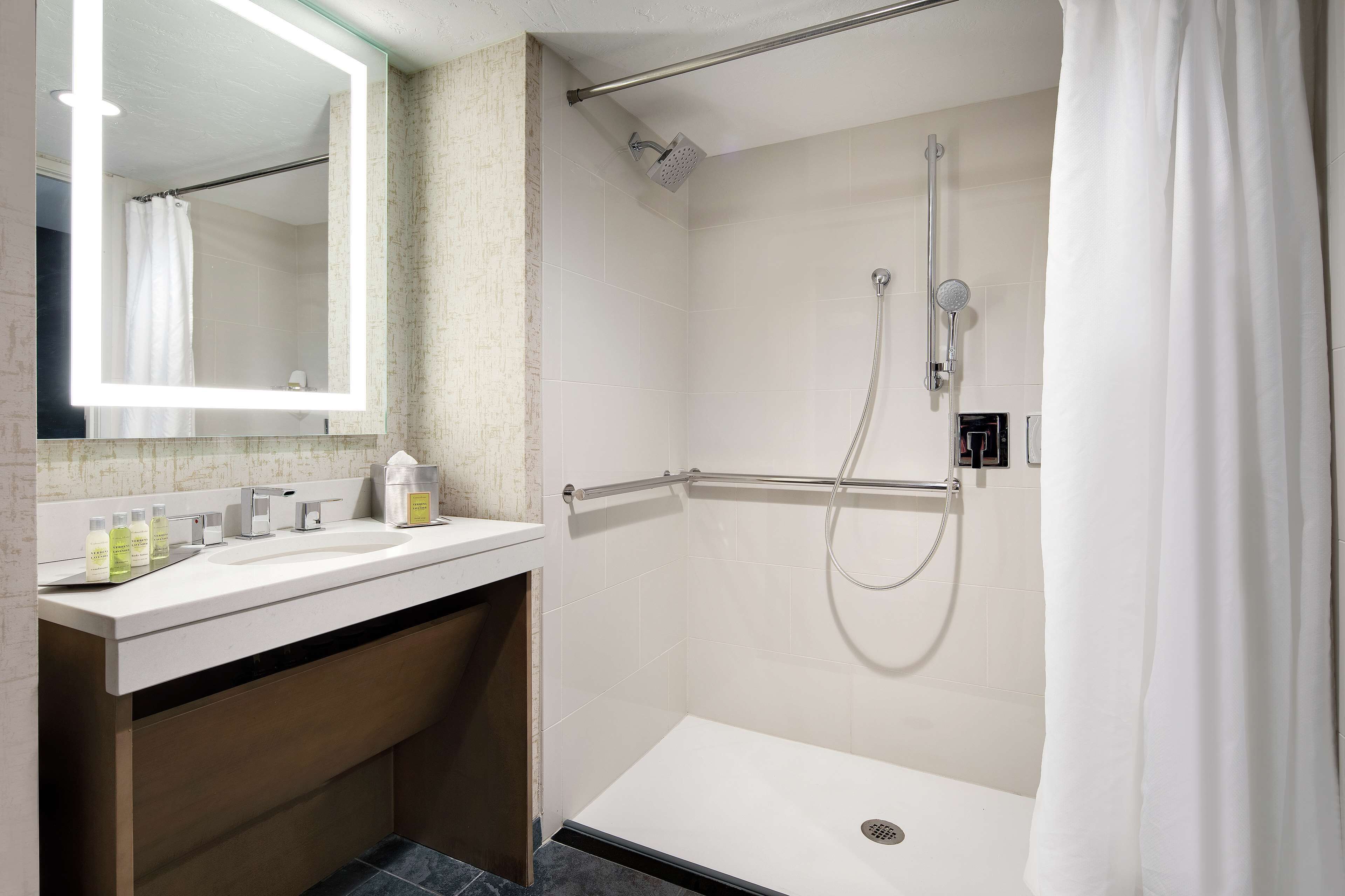 Une salle de bain moderne avec un lavabo blanc, un miroir et un espace douche.