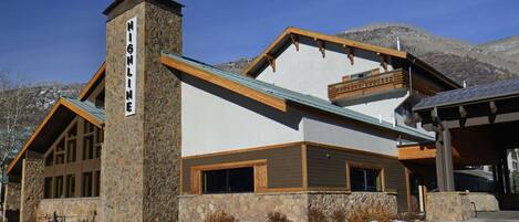 Un chalet doté d’une façade en pierre, de grandes fenêtres et d’une cheminée imposante.