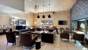 A modern hotel lobby with wooden walls, a large sofa, multiple chairs, a coffee table, and pendant lighting. - Highline Vail - a DoubleTree by Hilton (Vail)