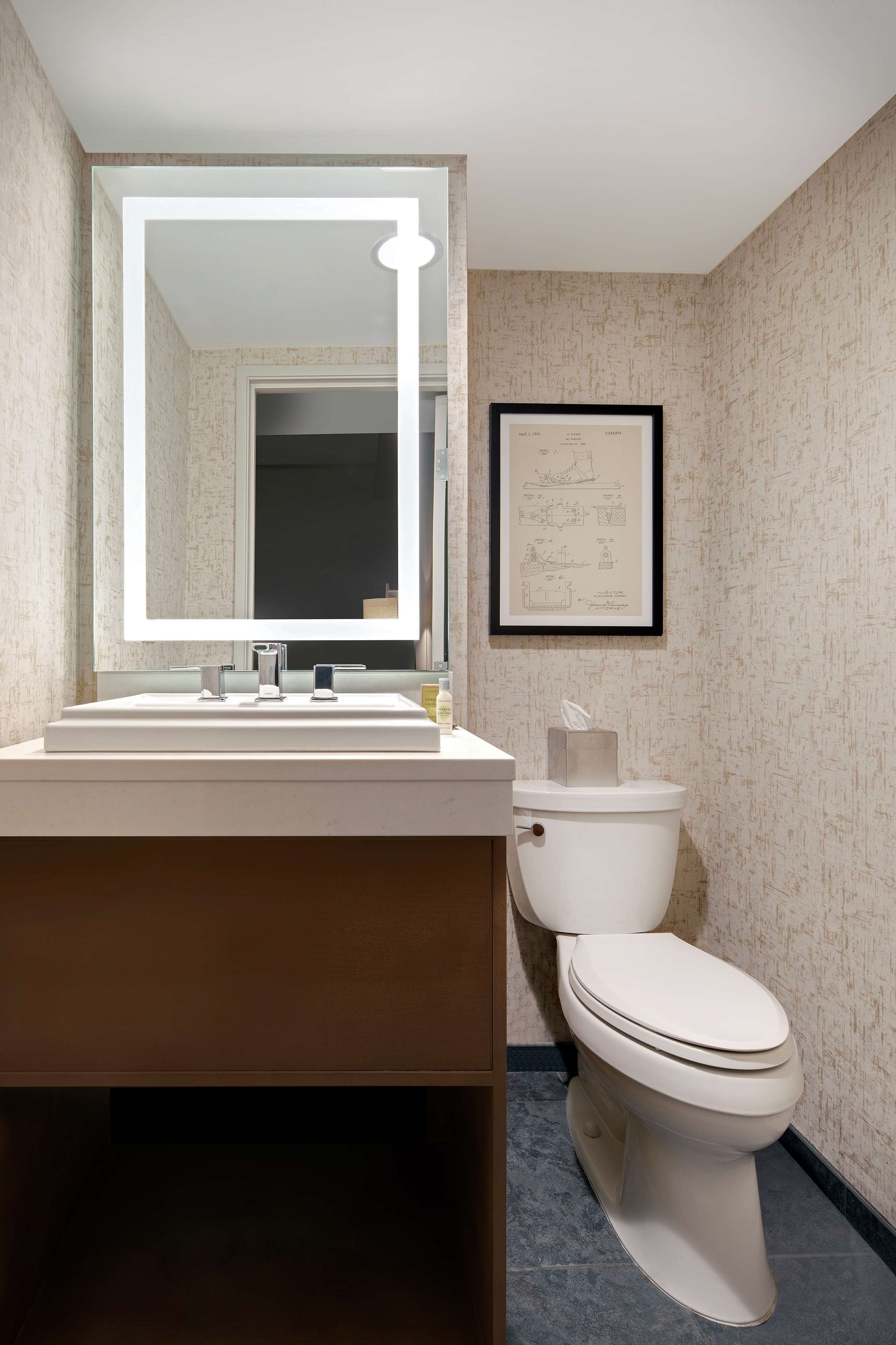 Een moderne badkamer met een grote spiegel, een witte wastafel en een toilet.