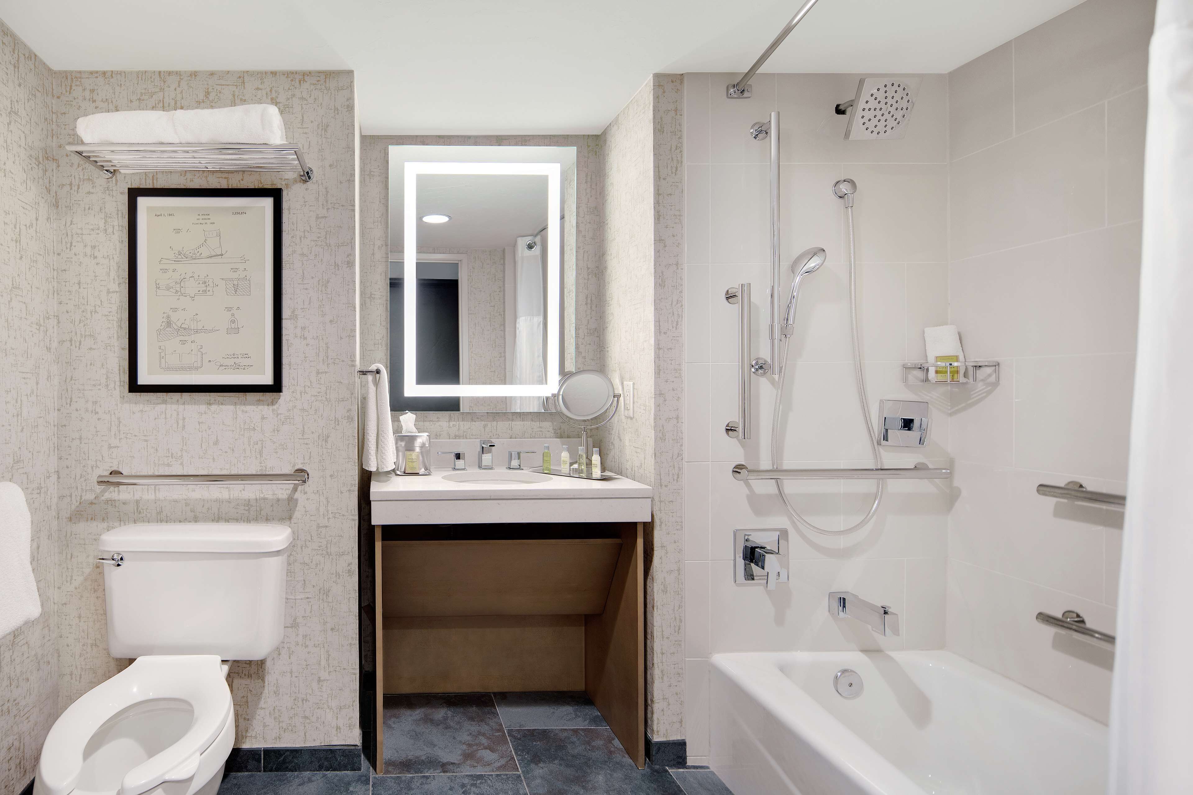 A modern bathroom with a toilet, sink, mirror, and shower.