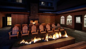 A patio with wooden chairs and a stone fire feature. - Highline Vail - a DoubleTree by Hilton (Vail)