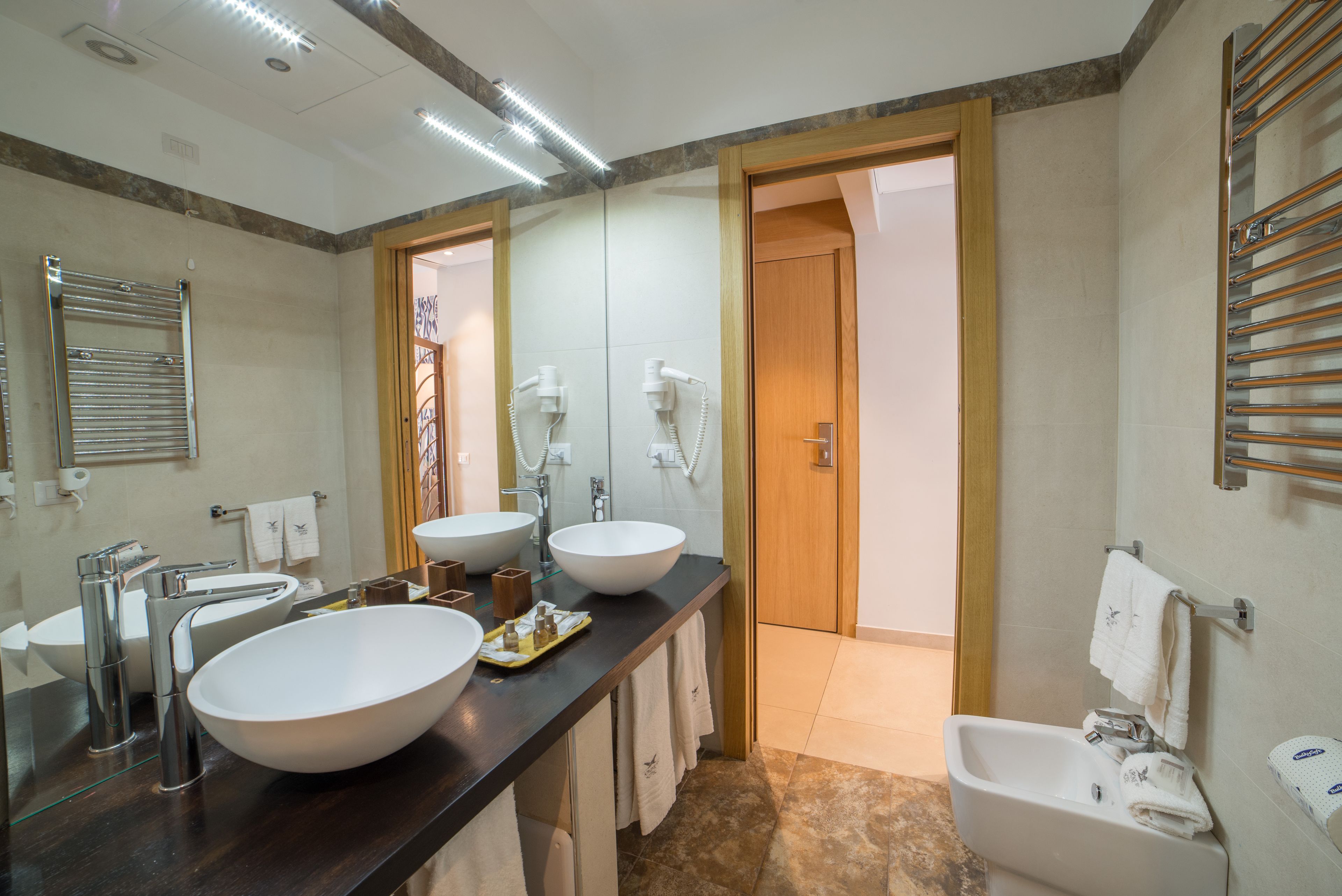 A modern bathroom with two large sinks, a vanity, and a shower area.