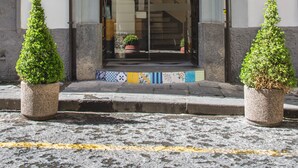 The exterior of the Airone Hotel with a classic facade, a stone entrance, and two potted plants on either side.