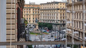 A view from a window overlooking a busy street with buildings and parked cars.