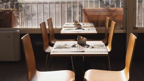 A dining area with a table set for two, chairs, and a window view.