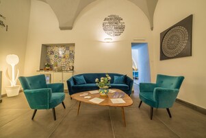 Un espace d’accueil avec des fauteuils de couleur turquoise, une table basse en bois, un canapé bleu et un mur orné d’un panneau représentant un nuage de mots.