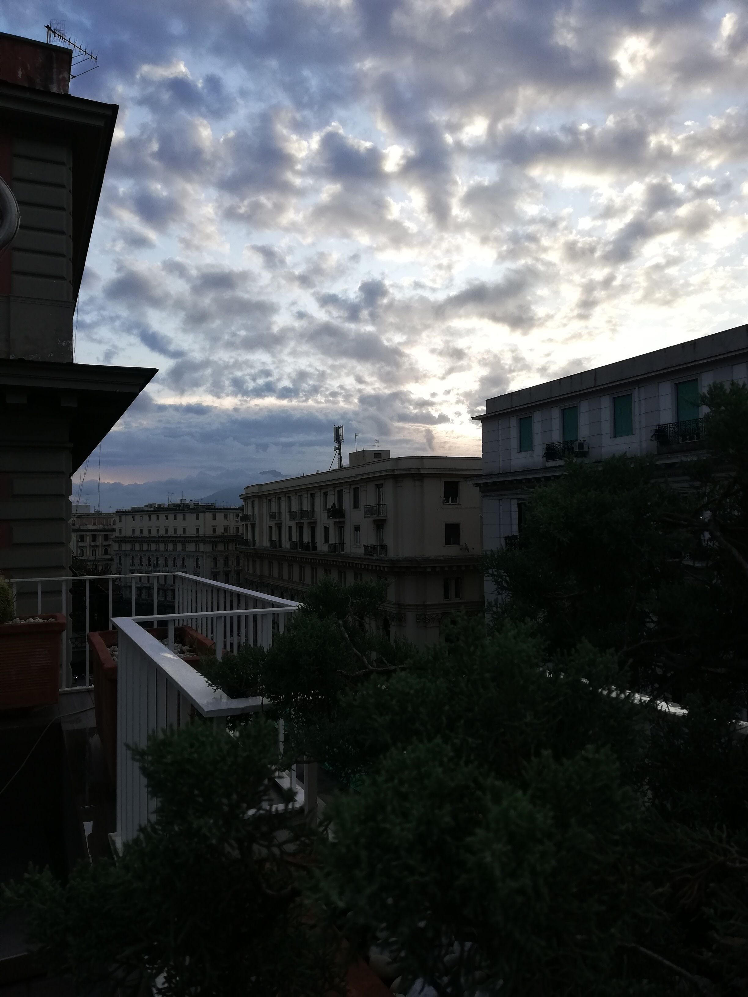 A building with multiple balconies and a view of the sky with clouds.