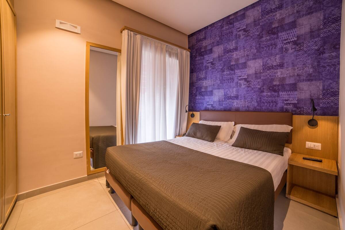 A neatly arranged hotel room with a bed, bedside tables, and a wall-mounted artwork.