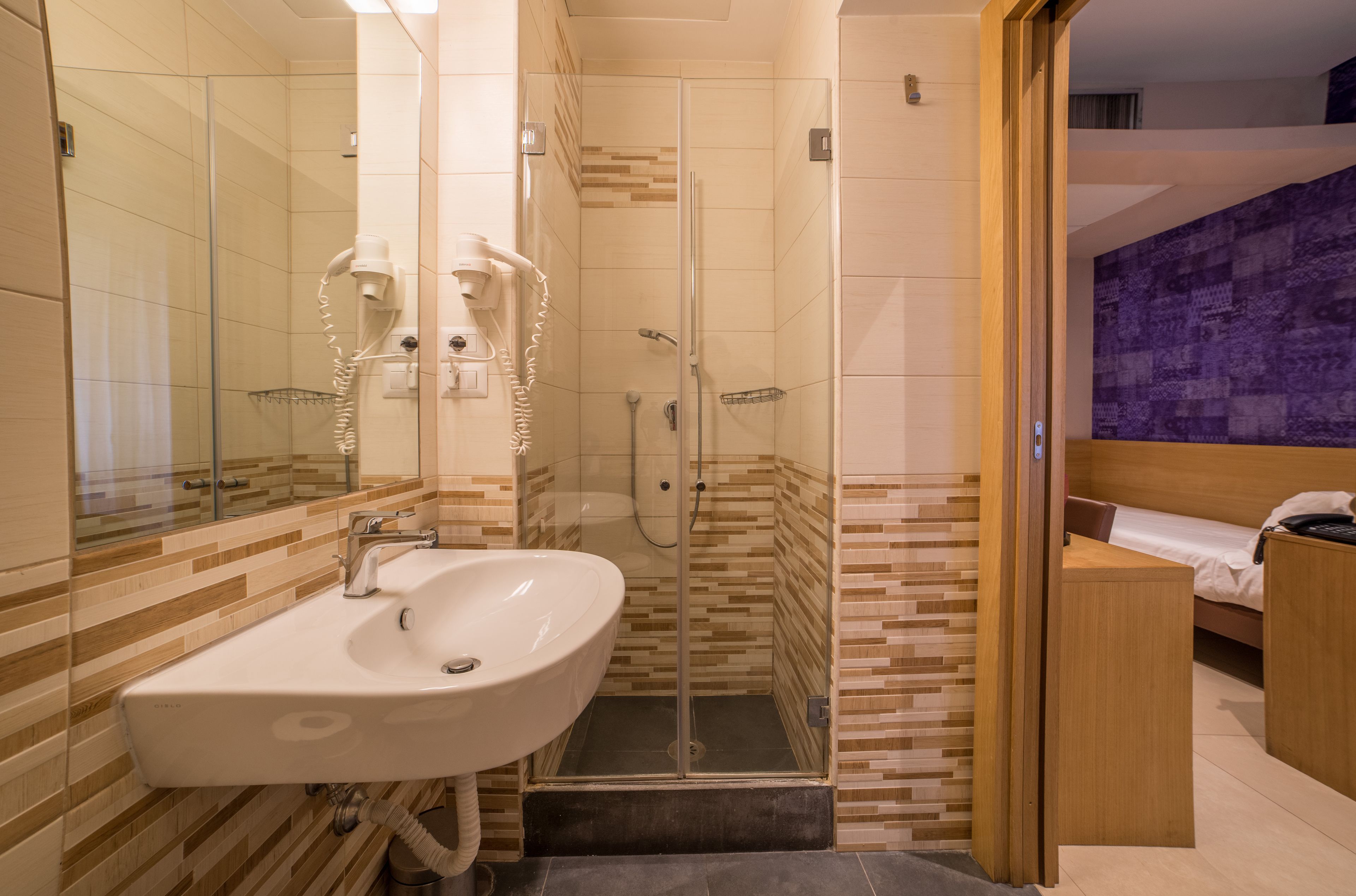 A modern bathroom with a glass-enclosed shower, a sink, and a mirror.