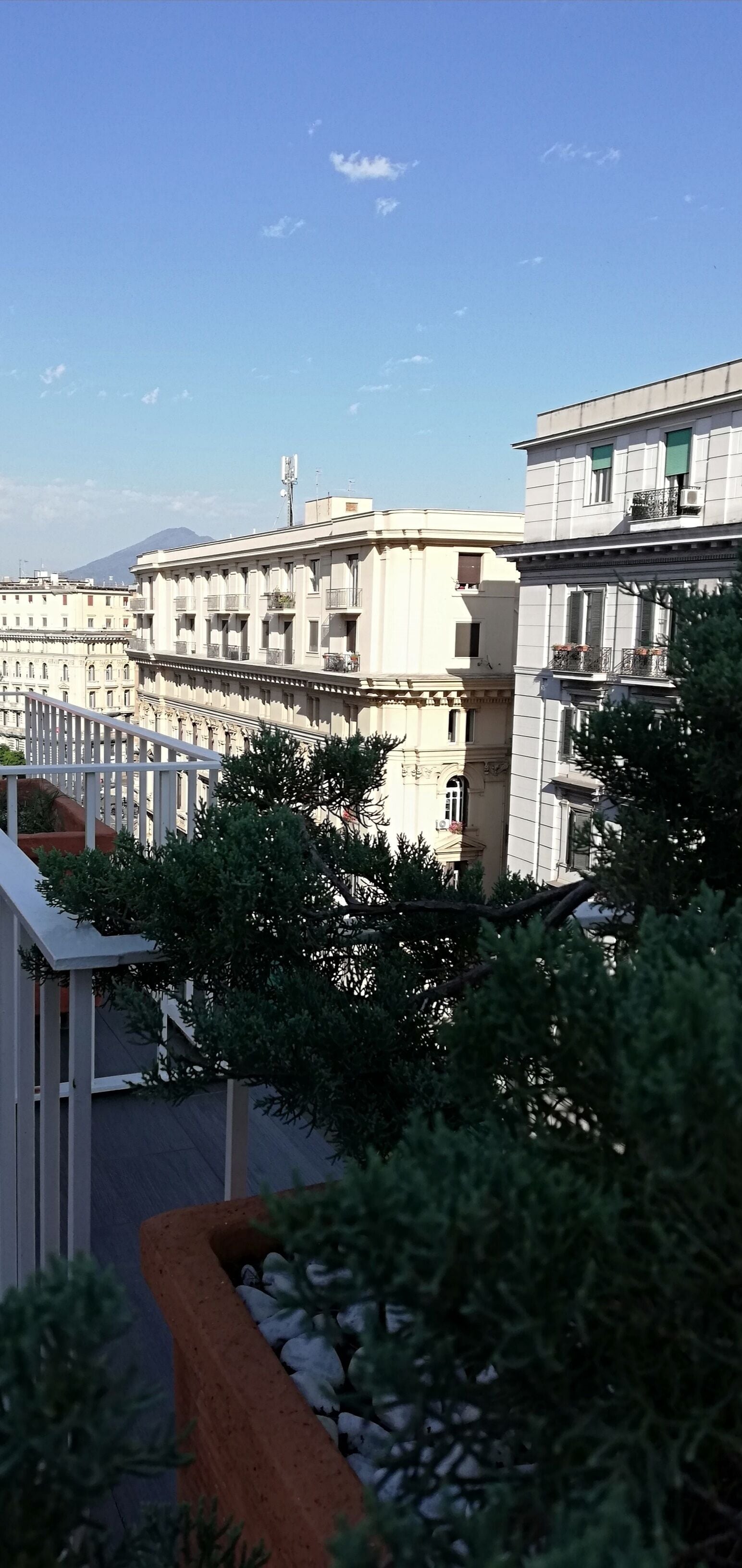 A row of buildings with balconies, a clear sky, and a mountain in the background.