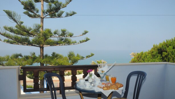 A balcony with a table set for breakfast, overlooking a coastal view. - Beach Hotel (Diamante)