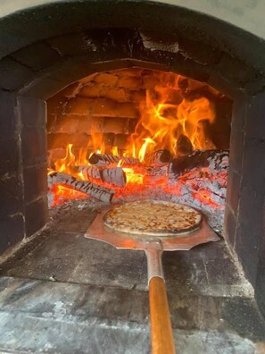 A pizza oven with a pizza inside, surrounded by flames.