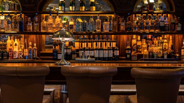 A bar with leather barstools and a variety of liquor bottles. - Headfort Arms Hotel (Kells)