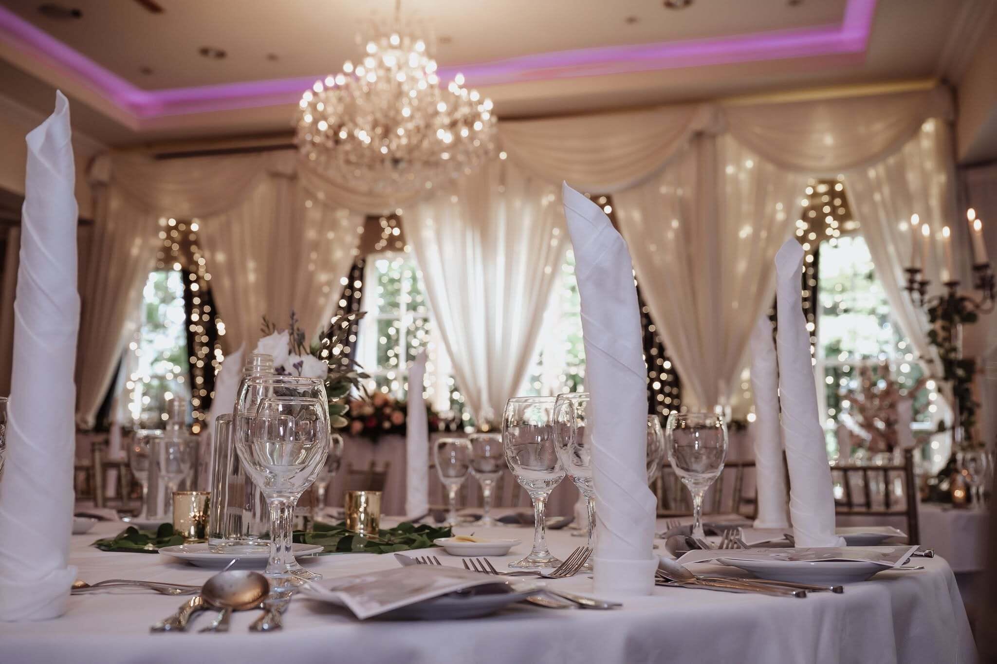 Escena formal a la taula de dinar preparada per a diversos comensals, amb vetreria transparent, serrarecords blancs i una presentació elegant.