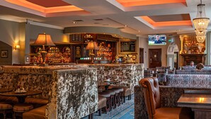 A bar area with a high counter, bar stools, and a television screen. - Headfort Arms Hotel (Kells)