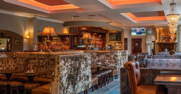 A bar area with a high counter, bar stools, and a television screen. - Headfort Arms Hotel (Kells)
