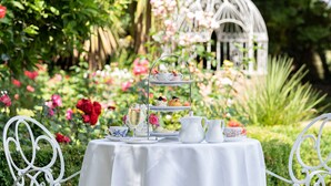 A garden setting with a table set for tea, including a teapot, cups, and a tiered tray with pastries. - Headfort Arms Hotel (Kells)