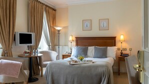 A hotel room with a bed, bedside lamps, a television, a desk with a lamp, and a chair. - Headfort Arms Hotel (Kells)