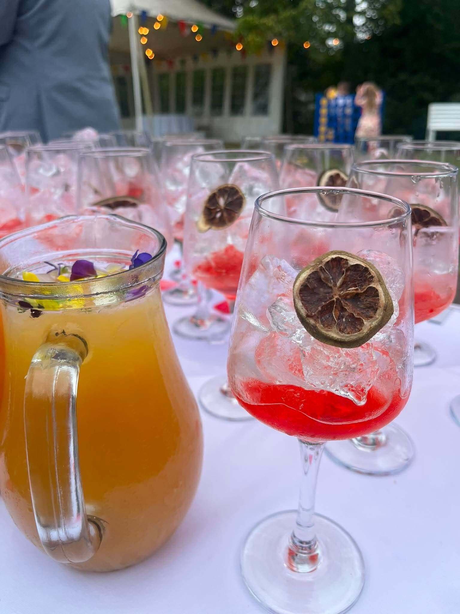 A table with various drinks in glasses, some with ice and garnishes.