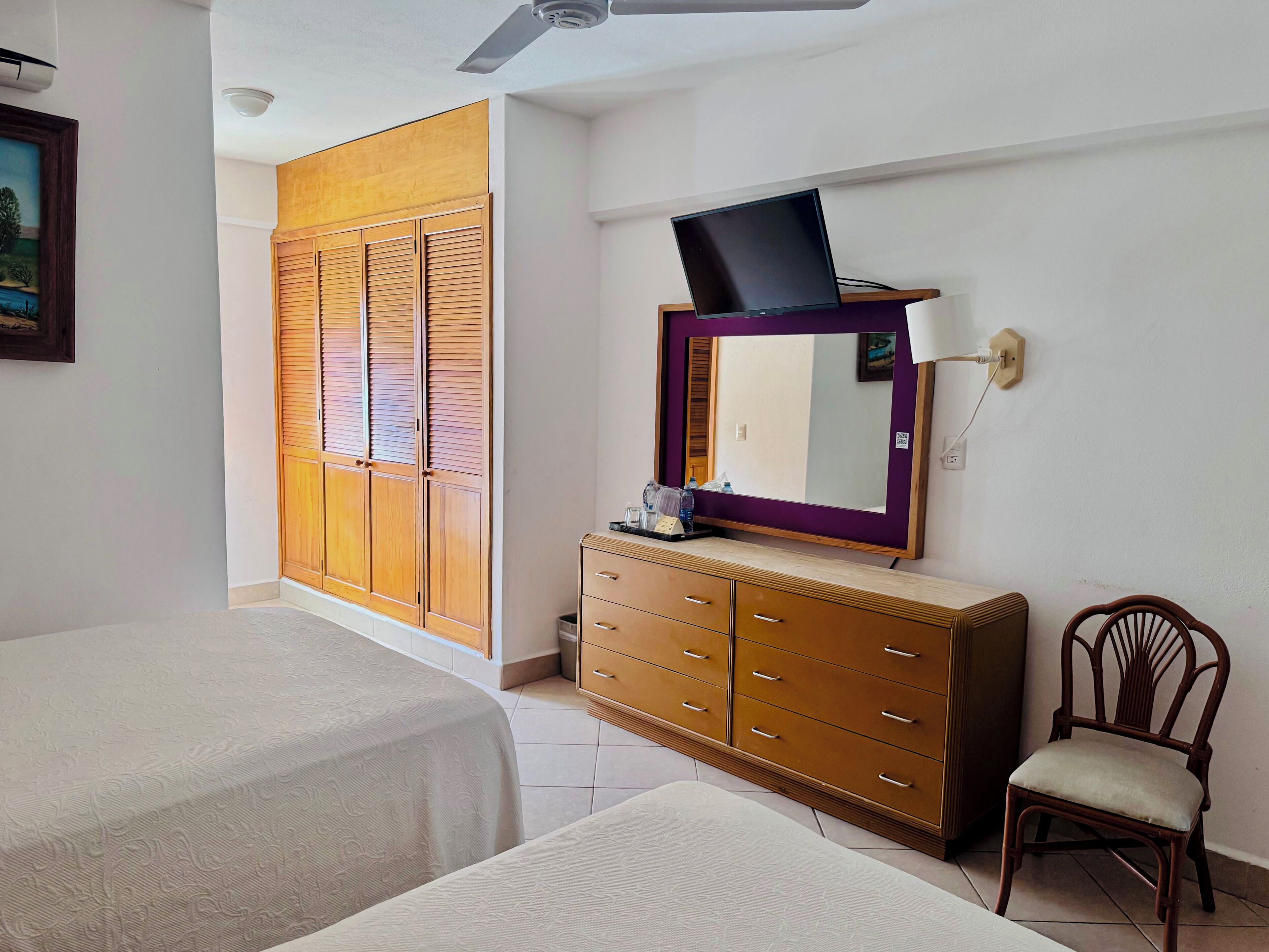 Una habitación de hotel con una cama, un aparador, una silla y un armario con puertas correderas.